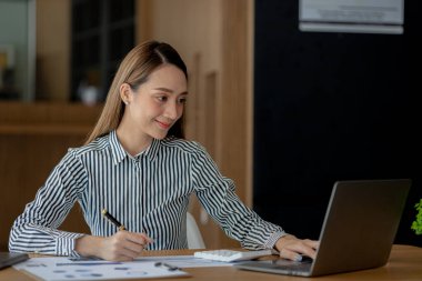 Güzel Asyalı genç bir kadın dizüstü bilgisayardan bilgilere bakıyor. Asyalı iş kadınının konsept görüntüsü. Zeki, modern kadın yönetici, girişimci iş kadını, iş kadını..