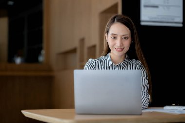 Güzel Asyalı genç bir kadın dizüstü bilgisayardan bilgilere bakıyor. Asyalı iş kadınının konsept görüntüsü. Zeki, modern kadın yönetici, girişimci iş kadını, iş kadını..