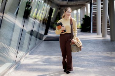 Üniversitede kitap çantasıyla yürüyen Asyalı bir kadın, sınıfa giren kız öğrenci, kız öğrenci. Üniversite eğitimi kavramı.