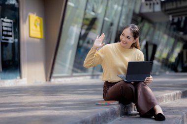Üniversite binasının merdivenlerinde tablet kullanan Asyalı bir kadın, kız öğrenci, sınıfa giren kız öğrenci. Üniversite eğitimi kavramı.