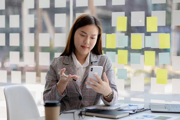 Özel bir ofiste oturan Asyalı güzel bir iş kadını, akıllı telefonuyla partneriyle video görüşmesi yapıyor, yeni başlayan bir şirketin kadın yöneticisidir. Finansal yönetim kavramı