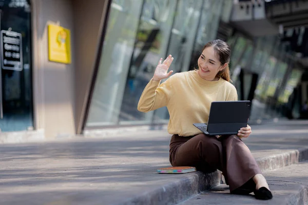Üniversite binasının merdivenlerinde tablet kullanan Asyalı bir kadın, kız öğrenci, sınıfa giren kız öğrenci. Üniversite eğitimi kavramı.