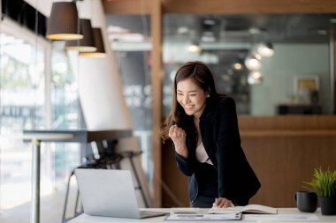 Kadın el kol hareketi yapıyor ve dizüstü bilgisayar ekranına bakıyor, iş kadını aylık satışları kontrol ediyor ve satış planlanan hedeflere ulaşırken mutluymuş gibi davranıyor. Satış yönetimi kavramı.