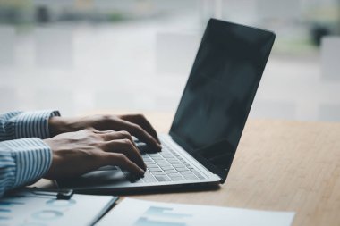 A business men working in a private room, He is typing on a laptop keyboard, He uses a messenger to chat with a partner. Concept of using technology in communication.