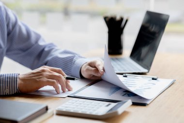 Businessman check to financial documents, he owns a startup company, he sits checking the company's financial summary prepared by the finance department. Management concept of startup company.