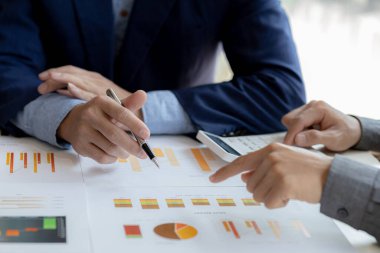 Company meeting room has businessmen and finance managers meeting together on finance topics, they are looking at information on documents and discussing together. Concept company financial management