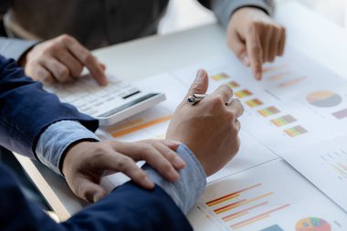 Company meeting room has businessmen and finance managers meeting together on finance topics, they are looking at information on documents and discussing together. Concept company financial management