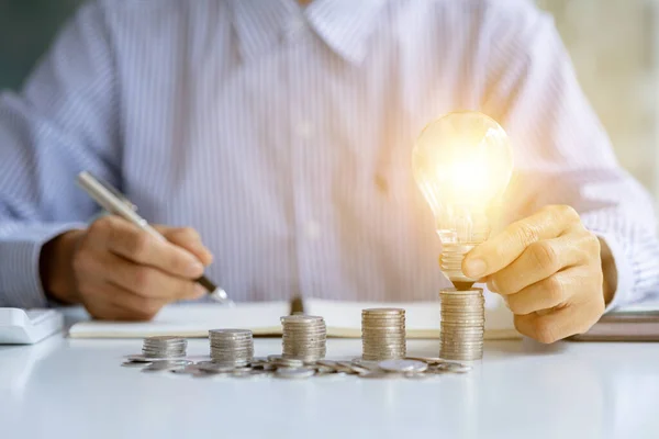 Businessman Holds Glowing Light Bulb Top Highest Pile Coins Placing — Fotografia de Stock