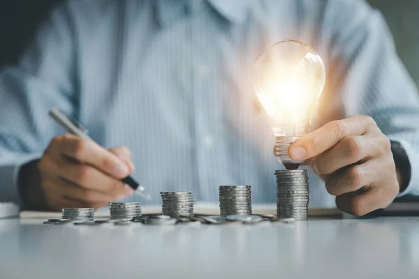 Businessman Holds Glowing Light Bulb Top Highest Pile Coins Placing — Fotografia de Stock