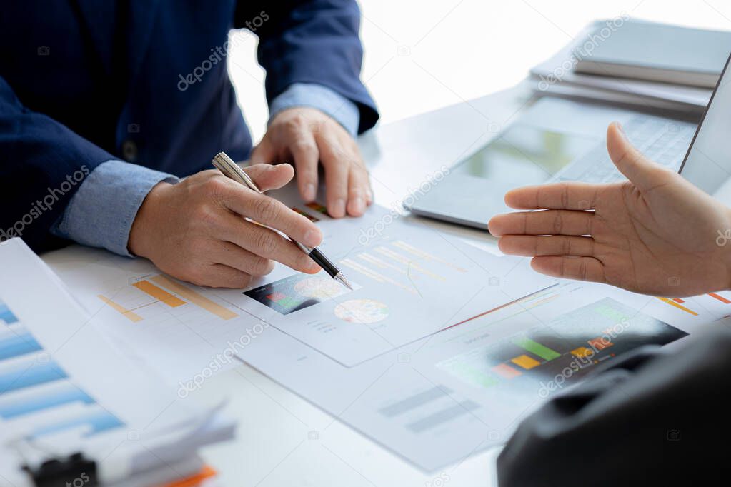 Company meeting room has businessmen and finance managers meeting together on finance topics, they are looking at information on documents and discussing together. Concept company financial management