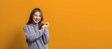 İlan metni için boş alanı işaret eden Asyalı kadın portresi, reklam ve tabela için kullanılan portre konsepti, sarı arkaplan üzerinde izole edilmiş, kopyalama alanı.