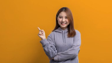 İlan metni için boş alanı işaret eden Asyalı kadın portresi, reklam ve tabela için kullanılan portre konsepti, sarı arkaplan üzerinde izole edilmiş, kopyalama alanı.