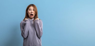 Güzel Asyalı kadın portresi, izole edilmiş mavi arka planda korku pozu veriyor, reklam ve tabela için kullanılan portre konsepti, mavi arkaplan üzerinde izole edilmiş, kopyalama alanı.