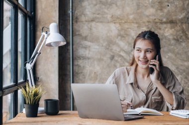 Telefonda konuşan Asyalı bir kadın, bir girişim şirketinde satış elemanı, ürün ve promosyon satmak için müşterileri arıyor. Telefon kanalları aracılığıyla ürün satma kavramı.