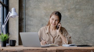 Telefonda konuşan Asyalı bir kadın, bir girişim şirketinde satış elemanı, ürün ve promosyon satmak için müşterileri arıyor. Telefon kanalları aracılığıyla ürün satma kavramı.