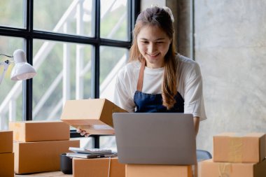 Güzel bir Asyalı işletme sahibi online bir dükkan açıyor, müşterilerin siparişlerini kontrol ediyor, bir kurye şirketi aracılığıyla mal gönderiyor, bir kadının online iş kurma kavramı.