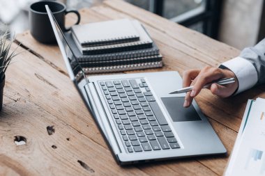 Özel bir odada çalışan yakın plan bir iş adamı, dizüstü bilgisayarda klavye kullanıyor, ortağıyla sohbet etmek için bir kurye kullanıyor. İletişim için teknoloji kullanma kavramı.