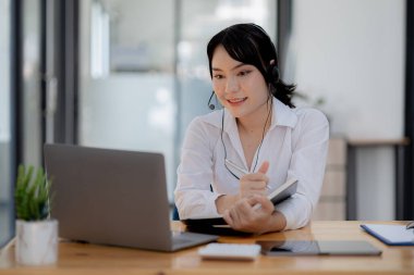 Güzel bir Asyalı kadın, bir internet ve telefon şirketinde çağrı merkezi çalışanı, telefon aracılığıyla müşterilere hizmet ve yardım sağlamaktan sorumludur. Çağrı merkezi kavramı.