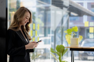 Pencerenin yanında cep telefonu çalan bir kadın, genç bir iş kadını ve genç bir yönetici sürekli yüksek kârlar elde eden bir girişim kurdular. Genç iş kadını ve girişimci şirket kavramı.