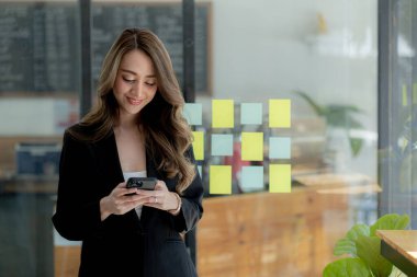 Pencerenin yanında cep telefonu çalan bir kadın, genç bir iş kadını ve genç bir yönetici sürekli yüksek kârlar elde eden bir girişim kurdular. Genç iş kadını ve girişimci şirket kavramı.