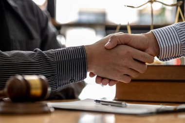 Avukatlar, bu işe ortak yatırım yapan iş ortaklarının zimmetine para geçirme davasında tanıklık etmeye gelen müşterilerle tokalaşıyorlar. Yasal işlemler için avukat tutma kavramı.