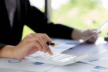 Businessman using a calculator to calculate numbers on a company's financial documents, he is analyzing historical financial data to plan how to grow the company. Financial concept.