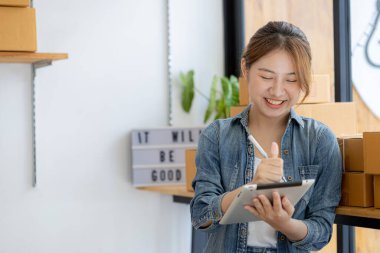 Online mağazanın sahibi satın alma miktarını kontrol ediyor ve teslimatı hazırlıyor, malları paketlemek için bir paket. Çevrimiçi satış ve online alışveriş kavramları.