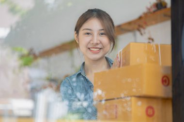 Güzel bir Asyalı işletme sahibi online bir dükkan açıyor, müşterilerin siparişlerini kontrol ediyor, bir kurye şirketi aracılığıyla mal gönderiyor, bir kadının online iş kurma kavramı.