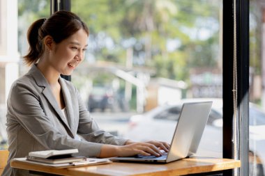Güzel Asyalı genç bir kadın dizüstü bilgisayardan bilgilere bakıyor. Asyalı iş kadınının konsept görüntüsü. Zeki, modern kadın yönetici, girişimci iş kadını, iş kadını..