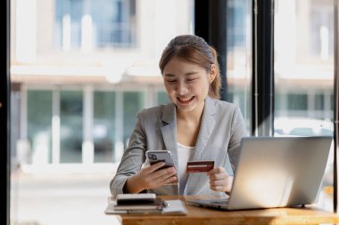 Kredi kartı tutan güzel bir kadın, internet üzerinden mal ve hizmetleri ödemek için kredi kartı kullanıyor, online alışveriş için kredi kartı kullanma kavramı, internet sitesinden mal ve hizmet sipariş etme kavramı.