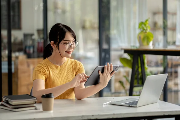 Young businesswoman looking at financial information from a tablet, she is checking company financial documents, she is a female executive of a startup company. Concept of financial management.