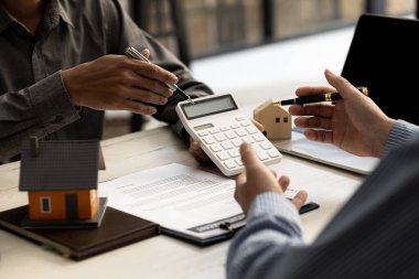 Bir kiralama şirketi çalışanı, kira sözleşmesi imzalamayı kabul eden müşterinin kira şartlarını ve koşullarını açıklayan maliyetini hesaplıyor. Ev ve gayrimenkul kiralama fikirleri.