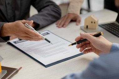 Kiralama şirketi çalışanı, müşteri kira sözleşmesini imzalamadan önce kira sözleşmesinin detaylarını ve şartlarını açıklamadan önce detayları tartışıyor. Emlak kiralama fikirleri.