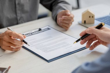 Rental company employee is discussing the details before the customer agrees to sign a rental contract, explaining the details and the terms and conditions of the rental. Real estate rental ideas.