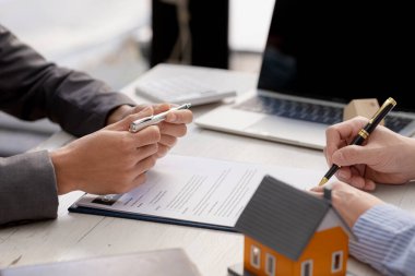 Kiralama şirketi çalışanı, müşteri kira sözleşmesini imzalamadan önce kira sözleşmesinin detaylarını ve şartlarını açıklamadan önce detayları tartışıyor. Emlak kiralama fikirleri.