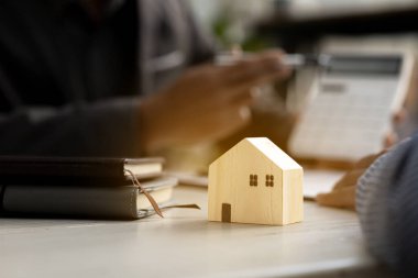 Küçük bir evin modeli emlak galerilerinden birinin kütüphanesinde duruyor. Satıcının müşterilere tavsiye verdiği örnek bir ev projesi. Projede ev satma kavramı.