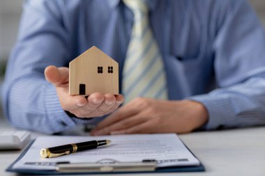 Bir yandan projeden sorumlu satış elemanı. Konut ve gayrimenkul satışı kavramı ve müşterilerle tanışmak için sözleşmeyi ve evin detaylarını hazırlıyor..