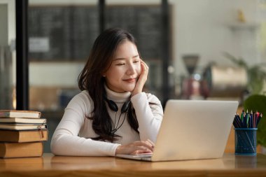 İnternette çalışmak için dizüstü bilgisayar kullanan güzel bir Asyalı kadın, çevrimiçi çalışıyor. Sınıfta bir salgını önlemek için COVID-19 salgını nedeniyle çevrimiçi öğrenme kavramı.