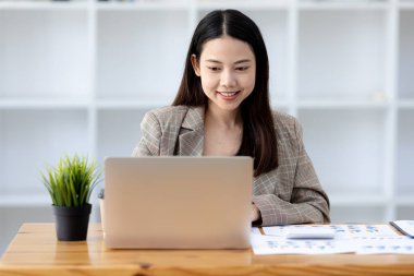 Güzel Asyalı genç bir kadın dizüstü bilgisayardan bilgilere bakıyor. Asyalı iş kadınının konsept görüntüsü. Zeki, modern kadın yönetici, girişimci iş kadını, iş kadını..