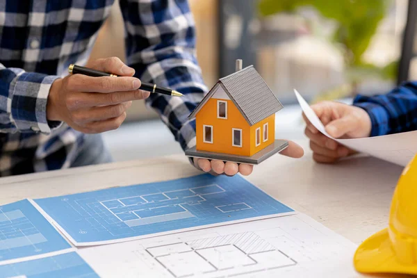 Architects design team is looking at models of small houses, Architect engineers design houses and interiors and draw floor plans through design program. Architect concept of building design.