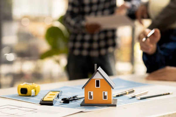 Close-up of a small house model, an architect engineer designs the house and its interior and draws a floor plan through a design program. Architect concept design house.