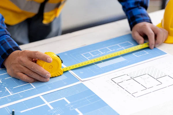 Architects are using tape measure to measure building plans, architect engineers design houses and interior structures and draw plans through design programs. Architect concept of building design.