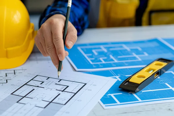 Architect pointing to building plans for review and editing, architect engineers design houses and interior structures and draw plans through design program. Architect concept of building design.
