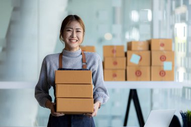 Güzel bir Asyalı işletme sahibi online bir dükkan açıyor, müşterilerin siparişlerini kontrol ediyor, bir kurye şirketi aracılığıyla mal gönderiyor, bir kadının online iş kurma kavramı.