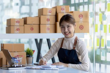 Güzel bir Asyalı işletme sahibi online bir dükkan açıyor, müşterilerin siparişlerini kontrol ediyor, bir kurye şirketi aracılığıyla mal gönderiyor, bir kadının online iş kurma kavramı.