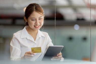 Beautiful woman holding a credit card, she uses a credit card to pay for goods and services online, the concept of using a credit card for online shopping, ordering goods and services on the website.