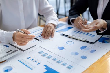 Two businessmen are reviewing the earnings summary and company financial documents that each department produces and submits for monthly audits. Concept of checking company information sheet.