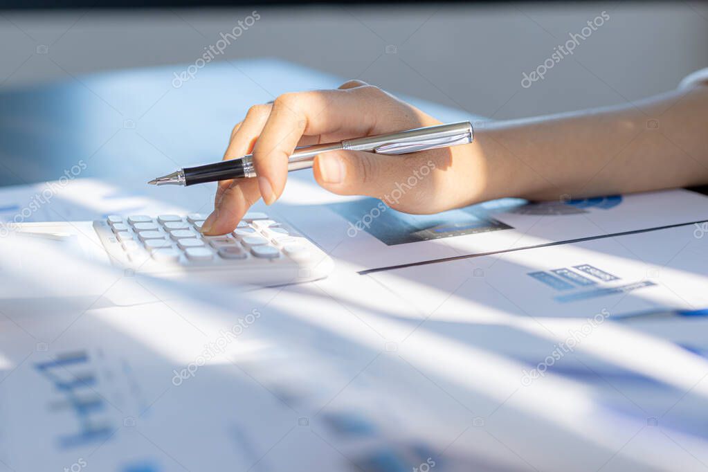 A business woman using a calculator to calculate numbers on a company's financial documents, she is analyzing historical financial data to plan how to grow the company. Financial concept.