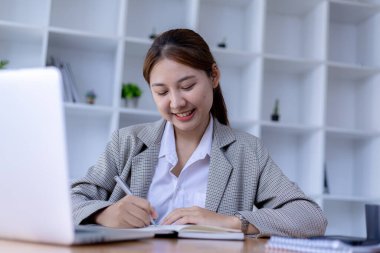 Asyalı bir kadın internetten aldığı dersleri not alıyor, o bir öğrenci. Sınıfta bir salgını önlemek için COVID-19 salgını nedeniyle çevrimiçi öğrenme kavramı.