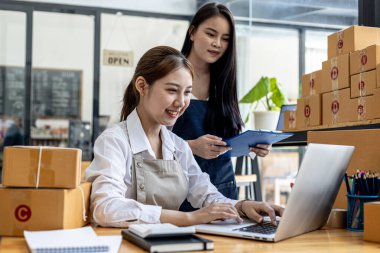 İki kadın çevrimiçi satıcı, konsept çevrimiçi ticaret şirketi, iki kadın satış elemanı müşterilere cevap veriyor ve müşterilerin internet sitesinden sipariş ettikleri siparişlere göre paketler hazırlıyorlar..